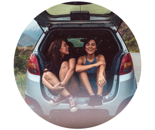Picture of two happy women sitting in the back of a SUV with tailgate open.